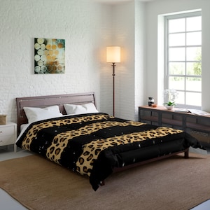 May include: A black and brown leopard print comforter with white accents. The comforter is on a bed with a brown wooden frame and is in a bedroom setting.