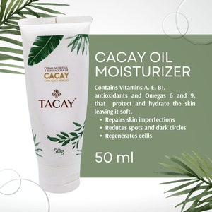 Puede incluir: Un tubo blanco de crema hidratante de aceite de cacay Tacay con hojas verdes en la etiqueta. El tubo es de 50g y contiene vitaminas A, E, B1, antioxidantes y omegas 6 y 9. Se dice que repara las imperfecciones de la piel, reduce las manchas y las ojeras y regenera las células.