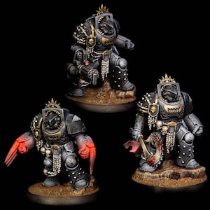May include: Three detailed miniature figures of armored warriors in a dark color scheme. Each figure is posed on a small, textured base. One figure wields a large weapon, another has red claw-like hands, and the third holds a gun.