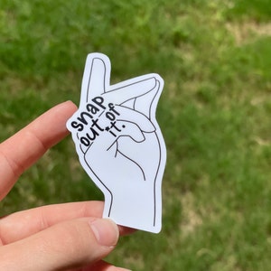 May include: White sticker with a black outline of a hand making a snapping gesture. The text "snap out of it." is written on the sticker.