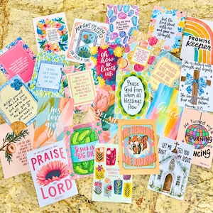 May include: A collection of rectangular cards featuring various colorful illustrations and religious text, including phrases like Praise the Lord, Promise Keeper, and Jesus is Big Dill, arranged in a scattered overlapping layout on a textured surface.