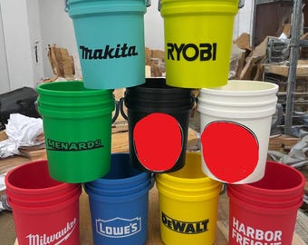 May include: An assortment of colorful plastic buckets with metal handles. The buckets are various colors, including teal, yellow, green, black, white, red, blue, and yellow. Each bucket has a brand name printed on it, such as "Makita", "Ryobi", "Menards", "Milwaukee", "Lowes", "Dewalt", and "Harbor Freight".