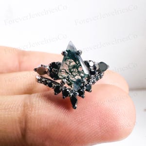 May include: A silver ring with a triangular green moss agate gemstone and black spinel accents.