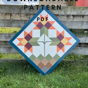 May include: A blue diamond-shaped sign with a quilt pattern in shades of orange, red, yellow, green, brown, and gray. The sign says "PDF" in the center and "DOWNLOADABLE PATTERN" at the top.