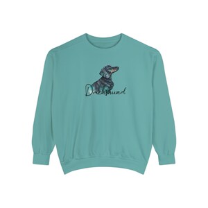 May include: A teal blue sweatshirt with a black and brown dachshund silhouette and the word "Dachshund" in black script.