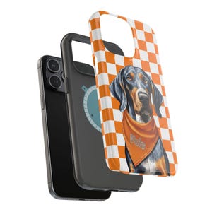 May include: A black and white checkered phone case with an orange and white checkered background. A black and brown dog with a bandana that says "Vols" is on the case.