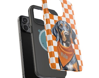 May include: A black and white checkered phone case with an orange and white checkered background. A black and brown dog with a bandana that says "Vols" is on the case.