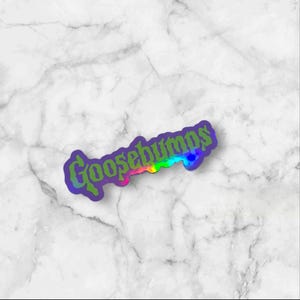May include: A die-cut sticker featuring the word Goosebumps in a stylized, gothic-inspired font. The lettering displays a vibrant, multi-colored gradient transition from green to yellow, orange, and pink, outlined with a dark purple border.