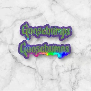 May include: Two die-cut stickers featuring the word Goosebumps in a stylized green font with a purple outline. The top sticker has a holographic star pattern, while the bottom sticker displays a vibrant rainbow gradient effect across the lettering.
