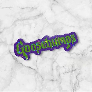 May include: A die-cut sticker featuring the word Goosebumps in a stylized, jagged green font with a dark purple outline. The design is accented with small, multicolored holographic star shapes scattered across the letters, creating a reflective effect.
