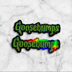 May include: Two die-cut stickers featuring the word Goosebumps in a stylized green font. The top sticker has a holographic finish with small star-shaped sparkles, while the bottom sticker displays a smooth, vibrant rainbow holographic effect.