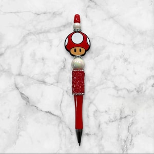 May include: A red and white pen with a mushroom-shaped top. The pen is decorated with white beads and rhinestones.