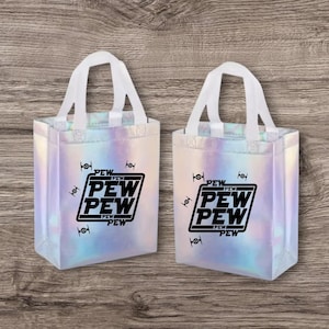 May include: Two iridescent tote bags with white handles. Each bag features the text "PEW PEW PEW" in a black rectangular design, along with small black spaceship graphics. The bags are on a wooden surface.