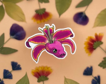 May include: A pink and yellow lily flower with a snake head in the center. The snake has a pink body with yellow spots and green eyes.