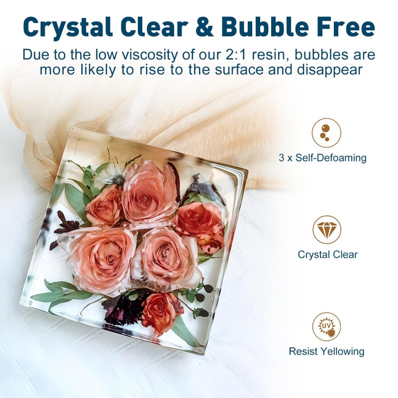 May include: A square clear resin block with a bouquet of pink and orange flowers inside. The resin is crystal clear and bubble free. The text "Crystal Clear & Bubble Free" is at the top of the image. The text "Due to the low viscosity of our 2:1 resin, bubbles are more likely to rise to the surface and disappear" is below the title. Three icons are shown below the text: a circle with three bubbles inside, a diamond, and a sun with a UV symbol inside. The text "3 x Self-Defoaming" is below the bubble icon. The text "Crystal Clear" is below the diamond icon. The text "Resist Yellowing" is below the sun icon.