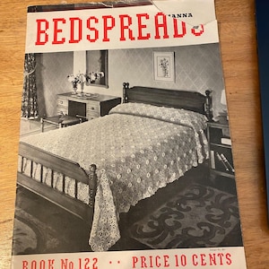 Peut inclure: Couverture de magazine vintage en noir et blanc, avec le titre "BEDSPREAD" en lettres rouges pixélisées. L'image montre une chambre avec un couvre-lit en dentelle sur le lit. Le texte "BOOK No.122 - PRICE 10 CENTS" est également visible.