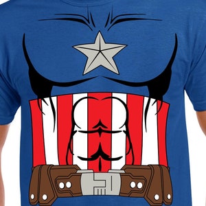 以下が含まれることがあります： スーパーヒーローの胸のプリントが施された青いTシャツ。赤、白、青の胸当て、星、ベルト付きです。