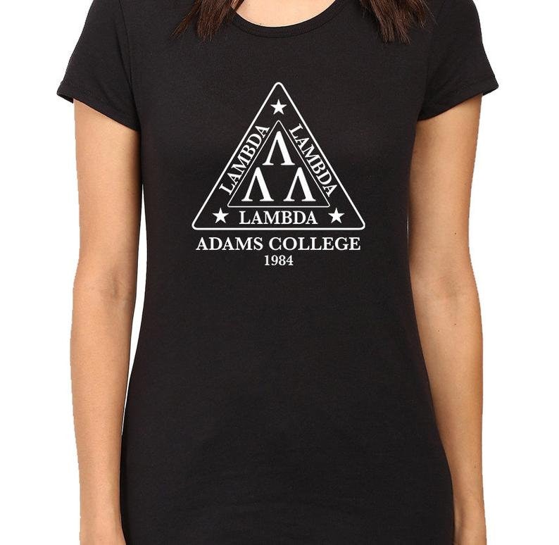 Może przedstawiać: Czarny T-shirt z białym tr&oacute;jkątnym logo z napisem "Lambda Lambda Lambda Adams College 1984".