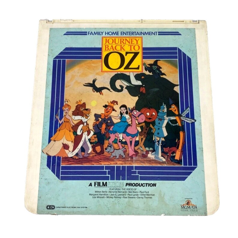 Puede incluir: Una portada de &aacute;lbum de vinilo vintage con una ilustraci&oacute;n colorida de personajes de la pel&iacute;cula "El Mago de Oz". La portada es azul y blanca con el t&iacute;tulo "El Mago de Oz" en letras grandes amarillas. Los personajes incluyen a Dorothy, el Espantap&aacute;jaros, el Hombre de Hojalata, el Le&oacute;n Cobarde y la Bruja Mala del Oeste.
