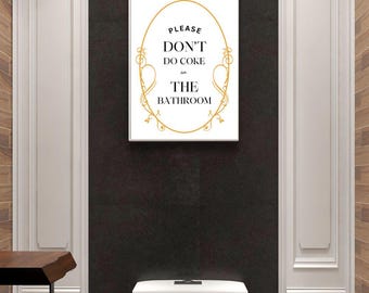 May include: White sign with a gold ornate border and the text "Please Don't Do Coke in The Bathroom". The sign is hanging on a black wall in a bathroom.