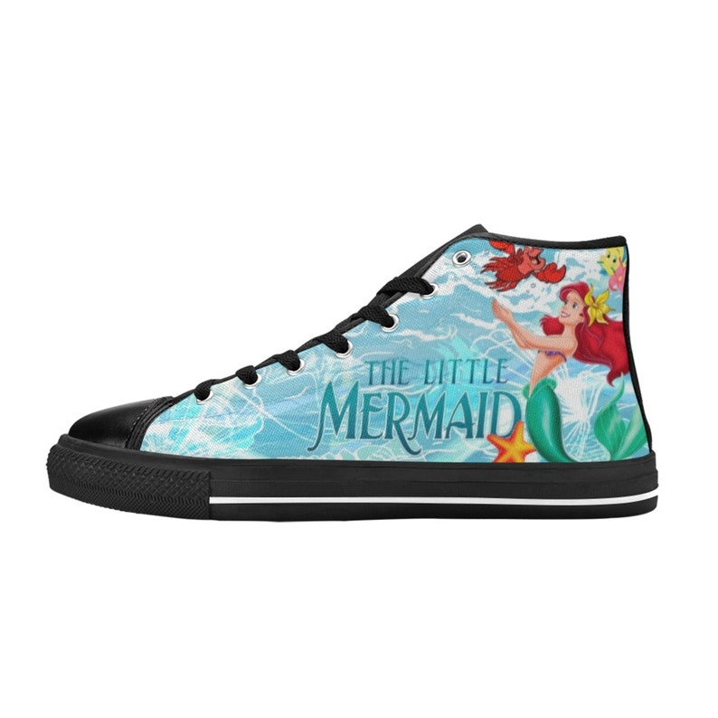 May include: High-top canvas sneaker featuring a design inspired by "The Little Mermaid." The shoe has a black toe cap and sole, with a light blue background and the movie's title. The design includes Ariel, a crab, and other characters.