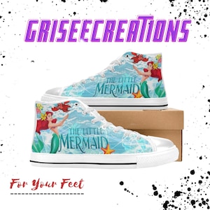 May include: High-top canvas sneakers featuring a design from "The Little Mermaid." The shoes are white with a light blue ocean-themed graphic, Ariel, and the text "The Little Mermaid." The shoes are on a cardboard box, with the text "For Your Feet."