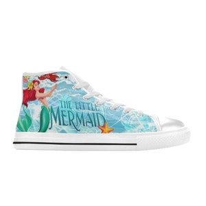 May include: White high-top canvas sneaker featuring a colorful design from Disney's The Little Mermaid. The design includes Ariel, a crab, and a starfish against a blue and white background. The words "THE LITTLE MERMAID" are also printed on the side.