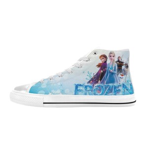 Puede incluir: Zapatillas blancas de lona de ca&ntilde;a alta con un dise&ntilde;o azul y blanco con los personajes de la pel&iacute;cula Frozen. Las zapatillas tienen la palabra "FROZEN" impresa en el lateral.