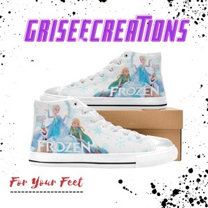May include: White high-top canvas shoes with a Frozen theme. The shoes feature images of Elsa, Anna, and Olaf from the Disney movie Frozen. The shoes have a white background with blue snowflakes and the word "Frozen" printed in blue.