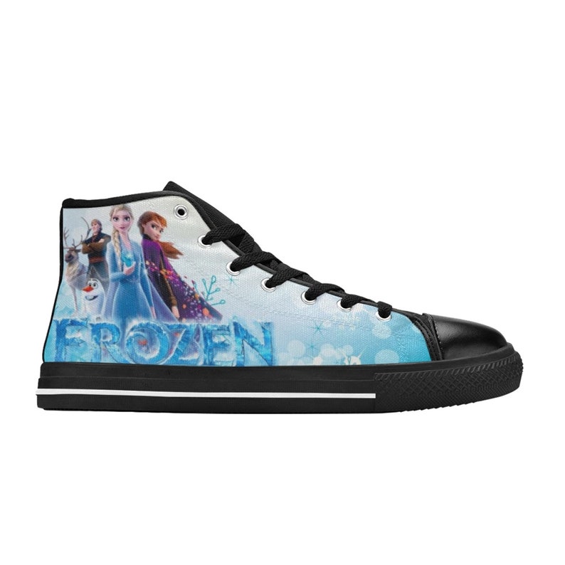 Puede incluir: Zapatillas de lona negras de ca&ntilde;a alta con fondo blanco con un tema de Frozen con Elsa, Anna y Olaf. Las zapatillas tienen cordones negros y una suela negra.