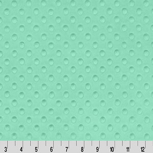 May include: A close-up of a light blue fabric with a textured pattern of small, raised circles. The fabric has a soft, plush feel.