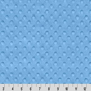 May include: A close-up of a light blue fabric with a textured pattern of small, raised circles. The fabric is soft and plush, perfect for baby blankets or other soft goods.