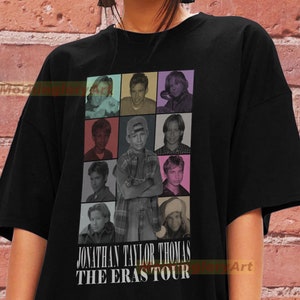 May include: Black t-shirt featuring a grid of nine images of Jonathan Taylor Thomas in various poses. The text "JONATHAN TAYLOR THOMAS THE ERAS TOUR" is printed below the images in white. The shirt is a casual, oversized style.