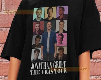Op de afbeelding: Zwart T-shirt met een collage van foto's van Jonathan Groff. De tekst "Jonathan Groff The Eras Tour" is onder de foto's gedrukt.