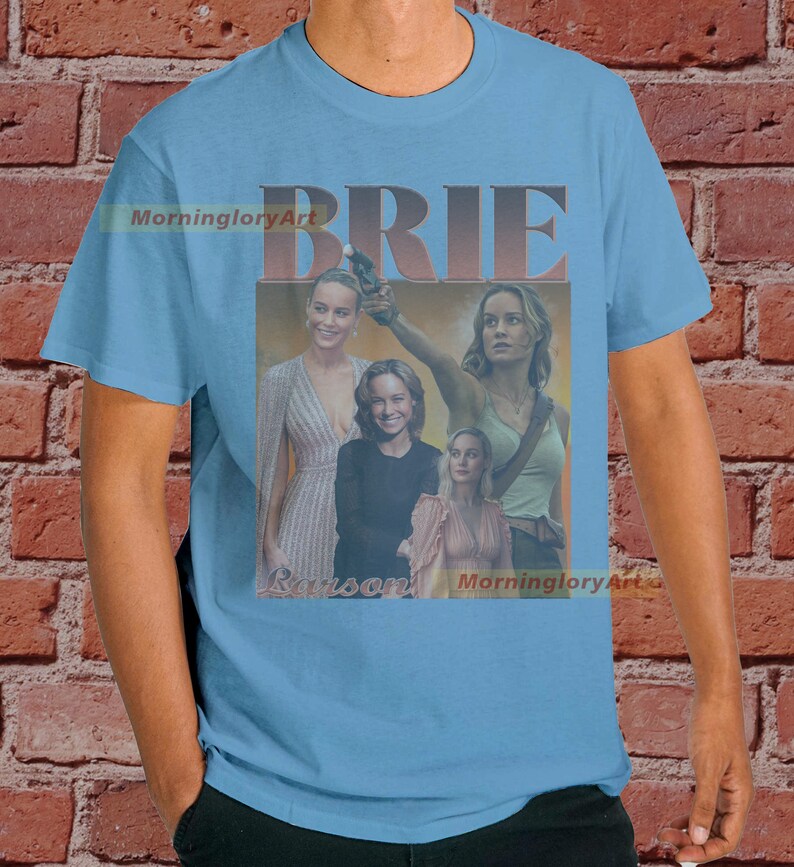 May include: A light blue t-shirt with a collage of images of Brie Larson. The text "BRIE" is in large, bold, brown letters. The text "Larson" is in smaller, brown letters. The text "MorninggloryArt" appears twice on the shirt.