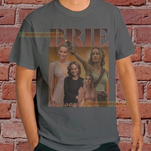 May include: A gray t-shirt with a collage of images of Brie Larson in different roles. The text "BRIE LARSON" is printed in a retro style font.