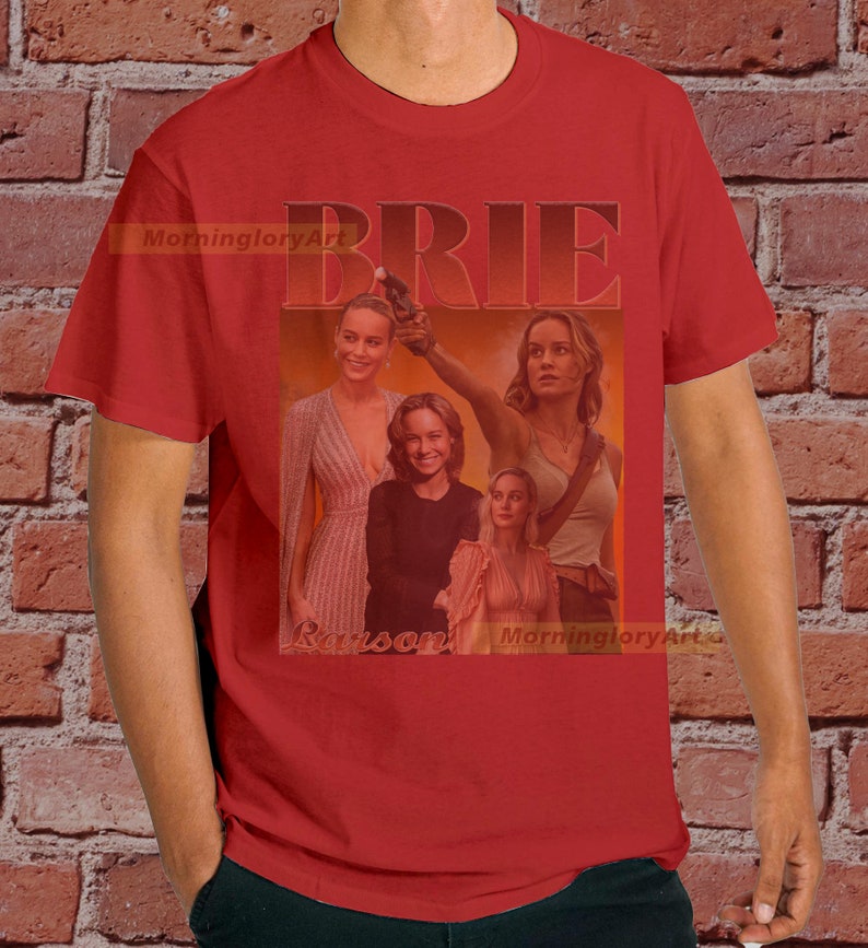 May include: Red t-shirt with a collage of images of Brie Larson, with the word "BRIE" in large, bold, white letters above the images. The text "Larson" is below the images.