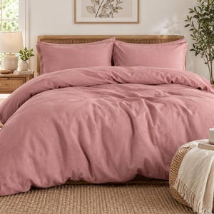 May include: A solid dusty rose duvet cover set featuring two matching rectangular pillow shams. The bedding is made of a textured fabric with a soft matte finish, providing a uniform color across the entire surface of the duvet and pillows.