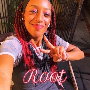May include: A person with long red and black braided hair wearing a black headband, a grey t-shirt with white trim, and a black dress. The word Root is written in a cursive red font across the center of the image. The person is making a peace sign.