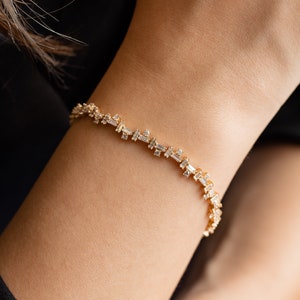 May include: A gold bracelet with a delicate chain and baguette-shaped diamonds.