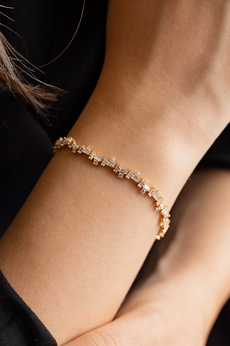 May include: A gold bracelet with a delicate chain and baguette-shaped diamonds.