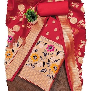 May include: A red fabric set featuring a large piece of cloth with gold floral patterns and a smaller solid red rectangular piece. The fabric displays intricate gold woven designs of flowers and leaves, with a wide border featuring yellow and pink floral motifs.