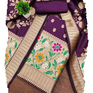 May include: A deep purple fabric with a wide gold border featuring a floral pattern in green, white, orange, and pink. The fabric has a smooth texture and includes a rolled piece of matching purple material and a small green artificial plant.