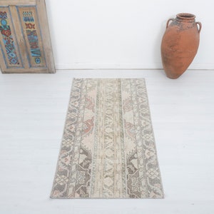 May include: A light beige runner rug with a traditional patterned design in shades of brown, pink, and gray. The rug has a distressed look and is perfect for adding a touch of vintage charm to any room.