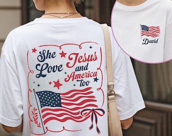 May include: White t-shirt with a patriotic design. The back features a red, white, and blue American flag graphic with the text "She Love Jesus and America Too." A smaller flag and the name "David" are on the front.
