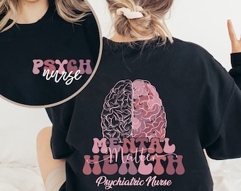 Könnte beinhalten: Schwarzer Pullover mit einem pinkfarbenen Gehirngraphic und dem Text "Mental Health Matters" in pinkfarbener Retro-Schrift. Der Text "Psychiatric Nurse" ist ebenfalls in Pink unter dem Grafikdruck.