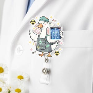 Pode incluir: Um porta-crachá com um pato de desenho animado vestindo um avental e boné de 'Rad Tech', segurando uma radiografia. O design inclui símbolos de radiação, ossos e brilhos. Possui um cordão retrátil branco e um fecho de pressão de plástico transparente.
