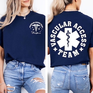 May include: Navy blue t-shirt with white text and graphics. The front features a caduceus symbol and the words "Vascular Access Team" and a name. The back displays a large white emblem with the words "Vascular Access Team".