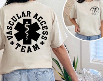 May include: Beige t-shirt with "VASCULAR ACCESS TEAM" printed in black around a black medical symbol on the back. The front of the shirt has a smaller matching design. The shirt is a crew neck.
