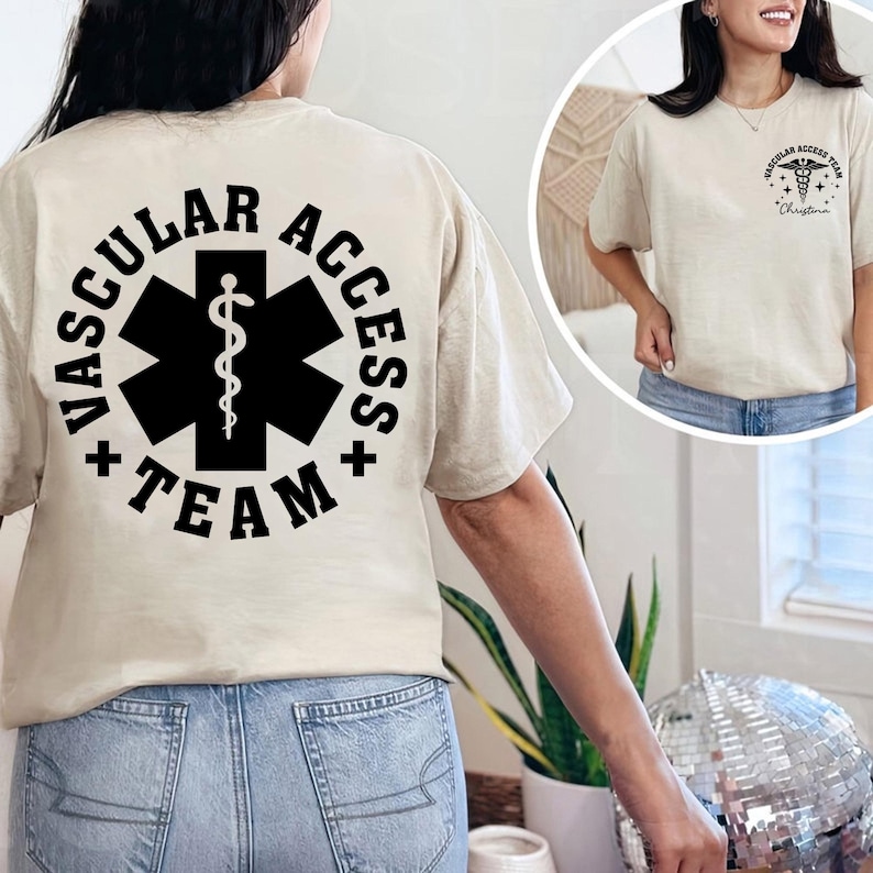 May include: Beige t-shirt with "VASCULAR ACCESS TEAM" printed in black around a black medical symbol on the back. The front of the shirt has a smaller matching design. The shirt is a crew neck.